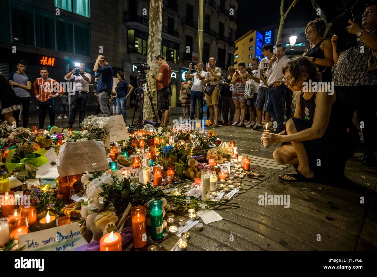 Barcelona, Spanien. 18 Aug, 2017. Ein trauernder Orte eine Kerze in einer provisorischen Denkmal an der Canaletas Brunnen in Las Ramblas, wo ein Van eine 550 Meter lange dschihadistischen Terror Reise gemacht. 13 Tote und fast 80 Verletzte, 15 ernst, als der van Riss durch die Menge der Credit: Matthias Oesterle/Alamy leben Nachrichten Stockfoto