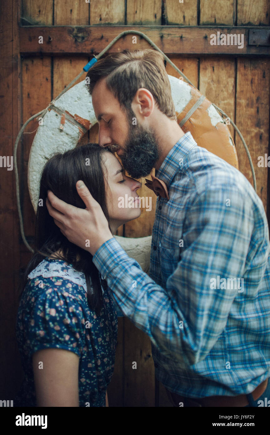Mann liebevoll küssen Frau auf Holz Wand Hintergrund Stockfoto