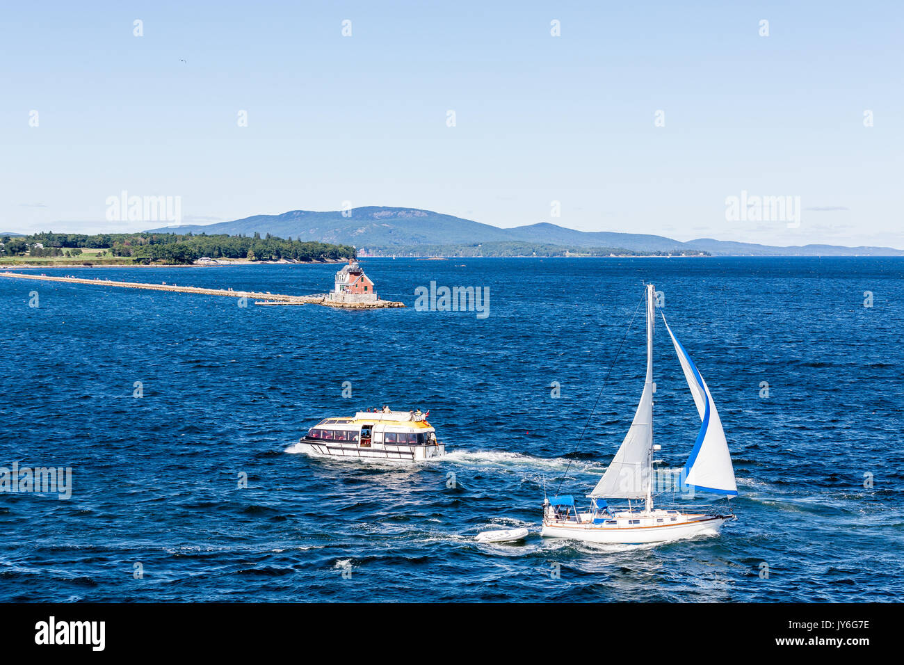 Eine kleine rote Leuchtturm an der Küste von Maine, in der Nähe von Rockland mit Segelboot und Royal Caribbean Rettungsboot Stockfoto
