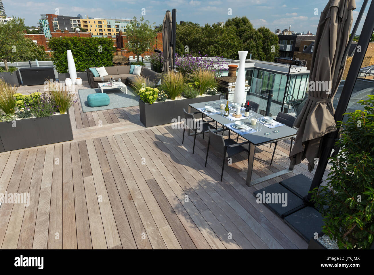 Luxuriöse Dachterrasse in London mit Schnittholz Terassendielen, zeitgenössische Pflanzmaschinen mit üppiger Bepflanzung und moderne Gartenmöbel Stockfoto