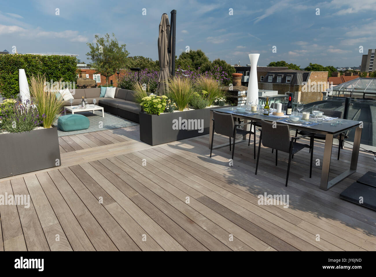 Luxuriöse Dachterrasse in London mit Schnittholz Terassendielen, zeitgenössische Pflanzmaschinen mit üppiger Bepflanzung und moderne Gartenmöbel Stockfoto