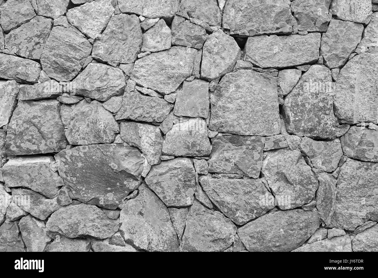 Alte Mauer in eine Festung aus Stein mit Flechten in Schwarz und Weiß. Stockfoto