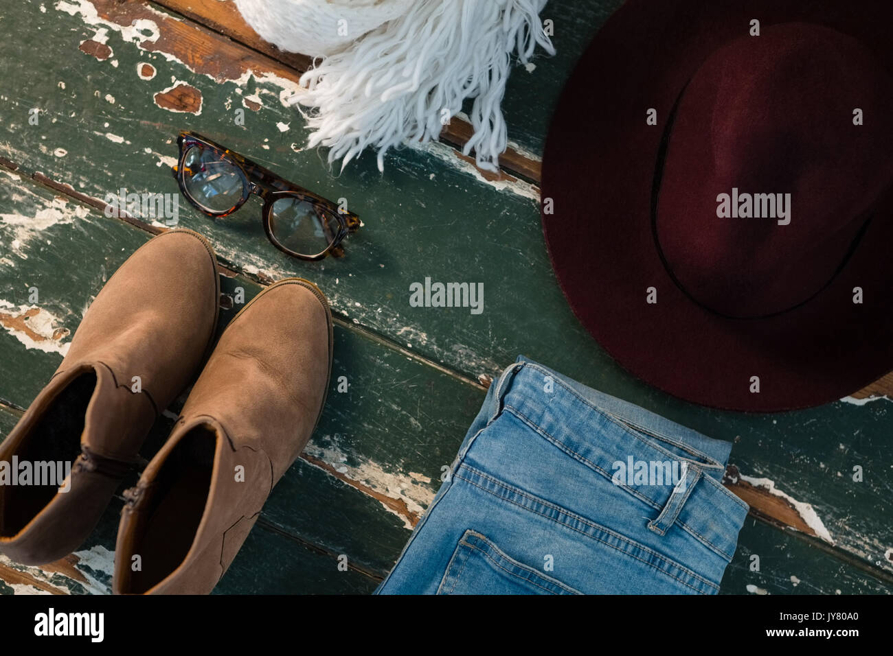 Hohe Betrachtungswinkel von Schuh- und Jeans mit persönlichen Accessoires auf hölzernen Tisch Stockfoto