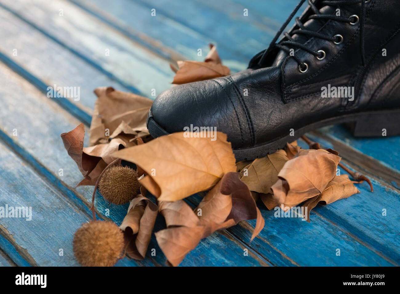 In der Nähe von Schwarzen Schuh durch die getrockneten Blätter auf hölzernen Tisch Stockfoto