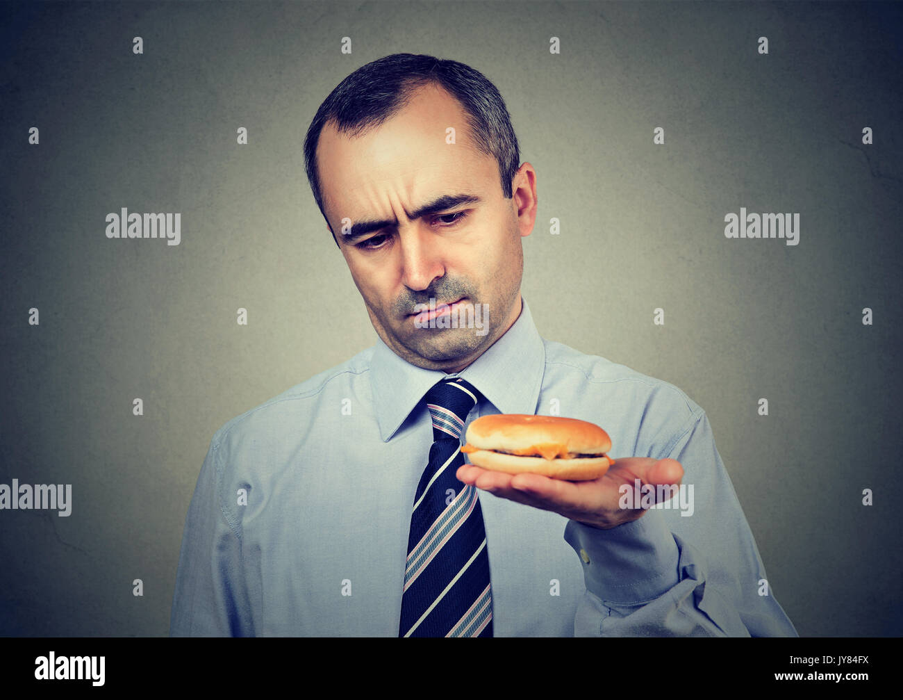 Ernster Mann an Cheeseburger suchen Stockfoto