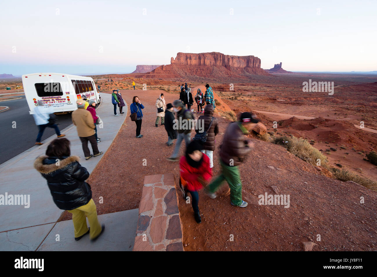 Monument Valley, Utah, USA. Eine Gruppe von asiatischen Touristen Spaziergang zu einem Aussichtspunkt an dem Monument Valley in der Nähe von Ihrer Tour Bus bei Sonnenaufgang. Stockfoto