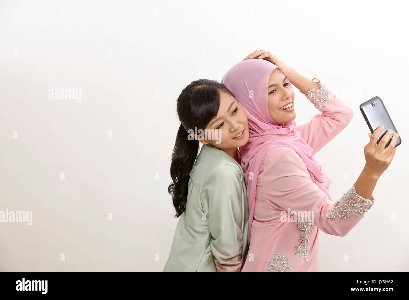 Zwei glückliche junge muslimische Frau, Selbstportrait mit Handphone Stockfoto