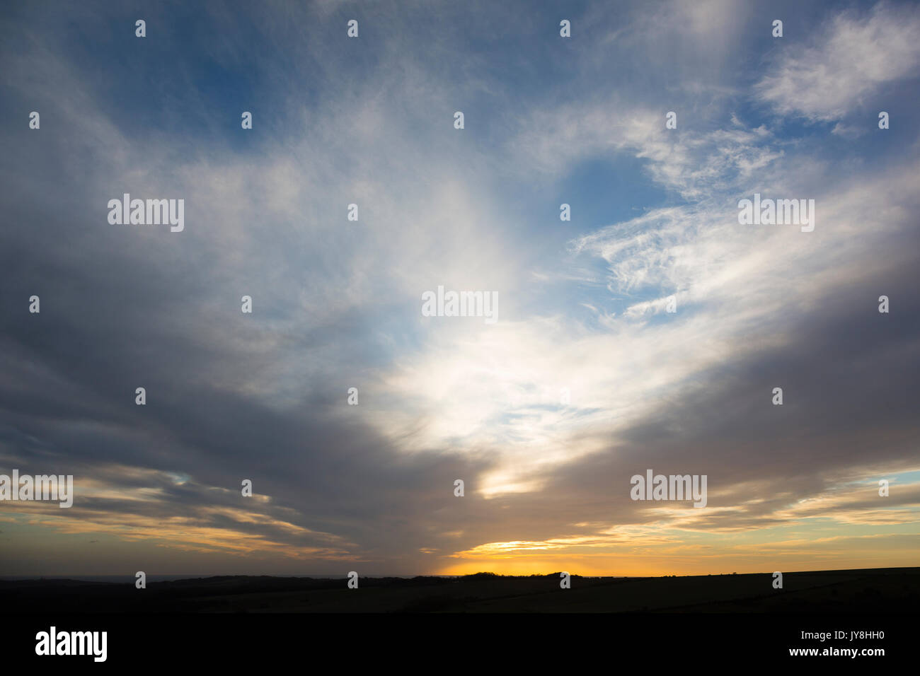 Ditchling Beacon, Sussex, UK. Wispy Wolken über einem tiefen orange Sonnenuntergang in Sussex. Stockfoto