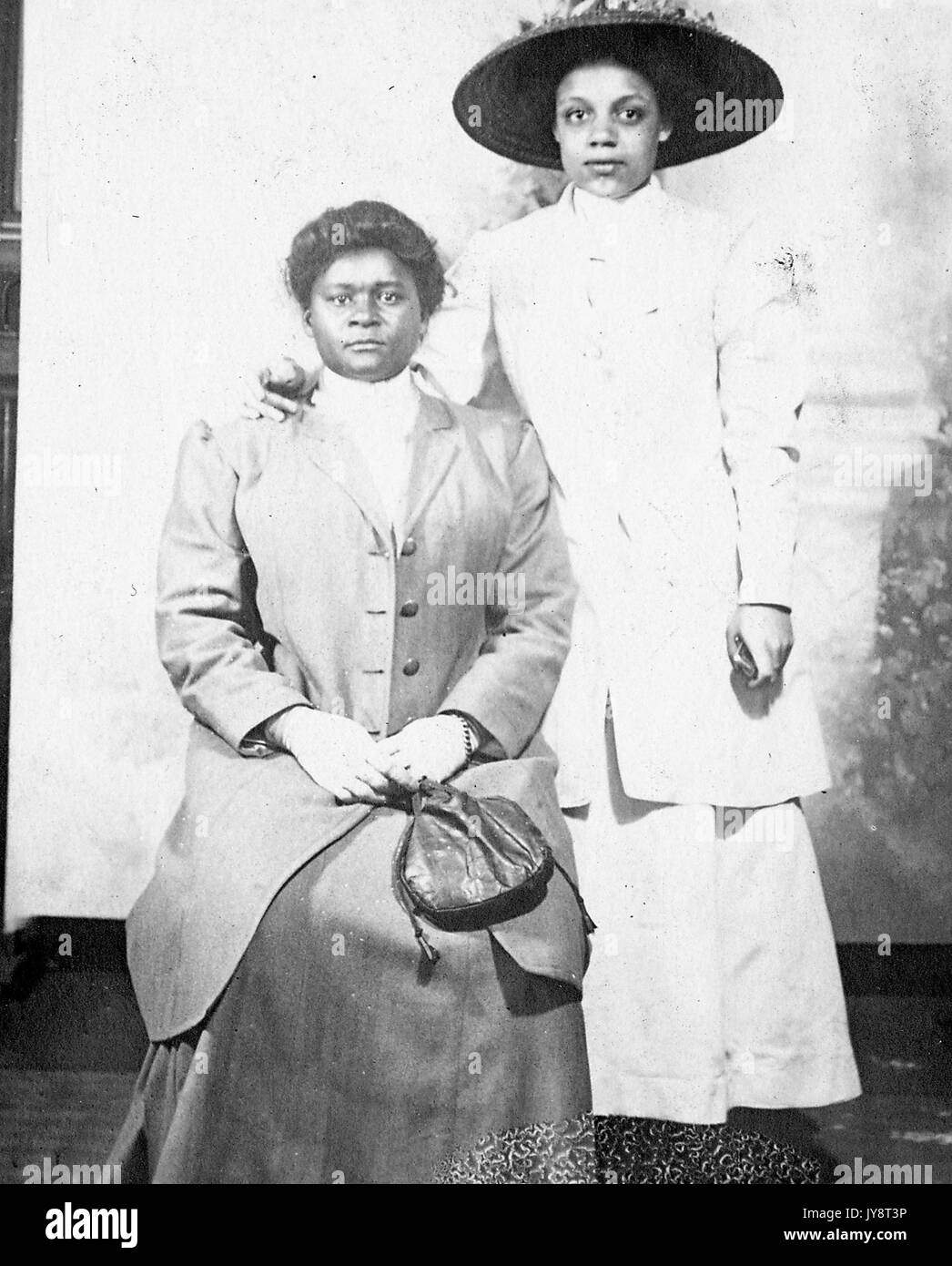 Porträt von zwei afrikanische amerikanische Frauen, beide trugen formale Kleider, einer sitzt, der anderen Stehen und legen ihre Hand auf die Schulter der ersten Frau, 1915. Stockfoto