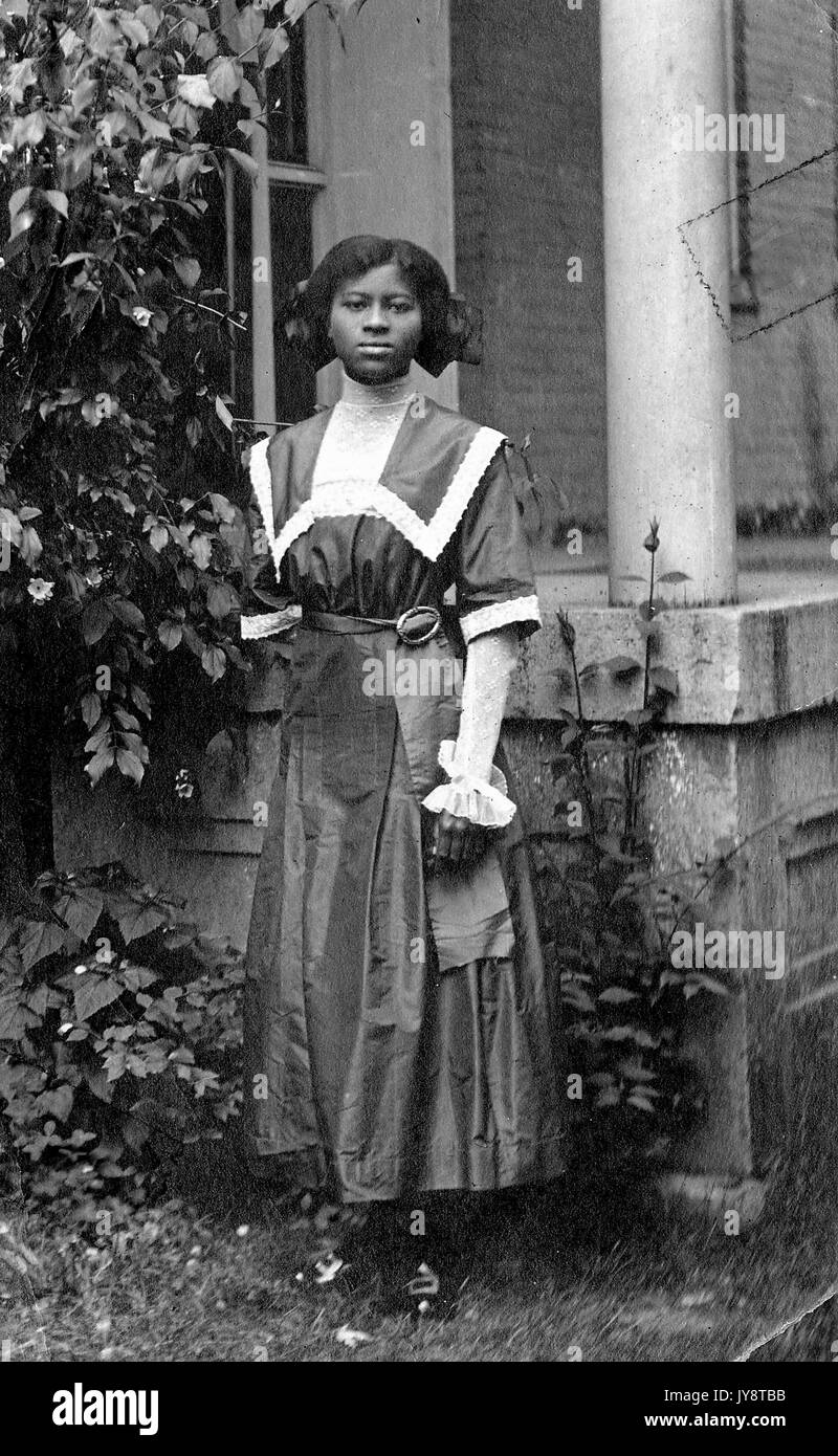 Ganzkörperportrait der jungen afroamerikanischen Frau, die ein formelles Kleid trägt und neben der Veranda eines Hauses steht, Florida, 1915. Stockfoto