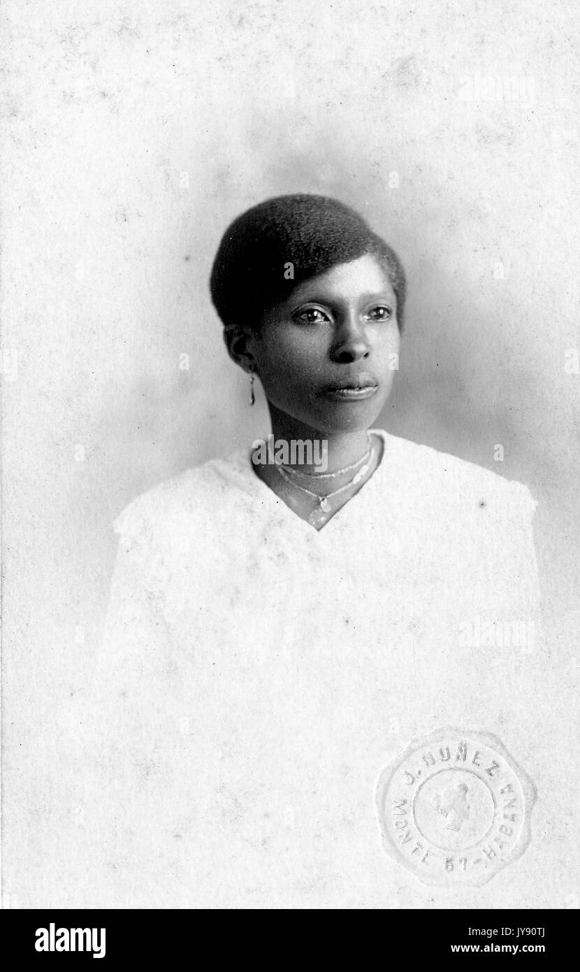 Taille bis Portrait von Sitzen afrikanische amerikanische Frau, trug ein weißes Kleid, Halskette und Ohrringe, mit einem ernsten Gesichtsausdruck, 1915. Stockfoto