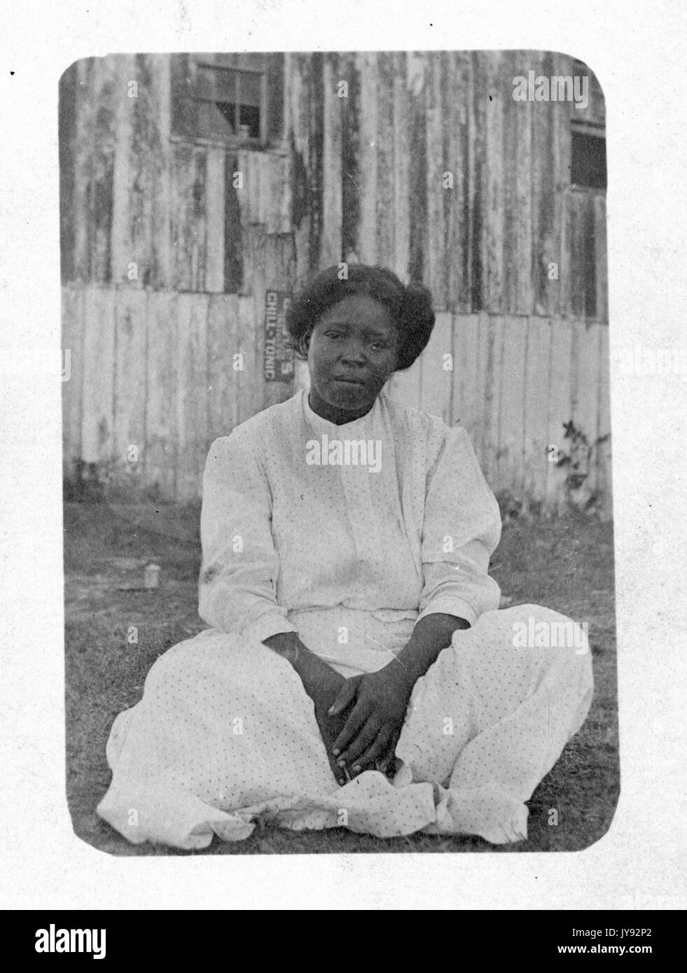 Porträt einer afroamerikanischen Frau in formaler Kleidung, mit Haus, sitzend mit gekreuzten Beinen, 1930. Stockfoto