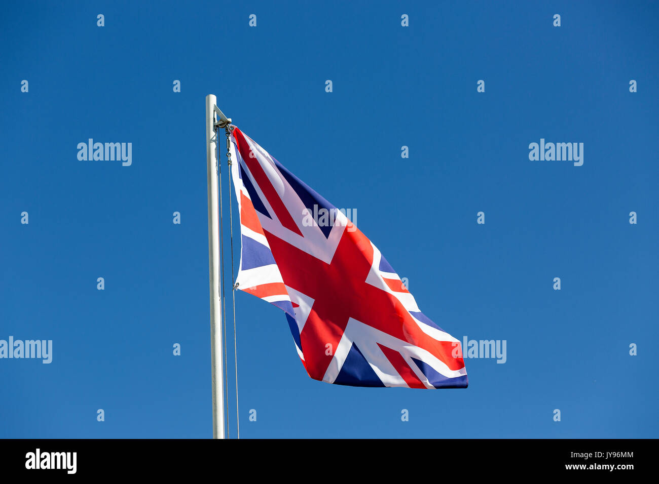 Britische Flagge am Fahnenmast vor blauem Himmel Stockfoto
