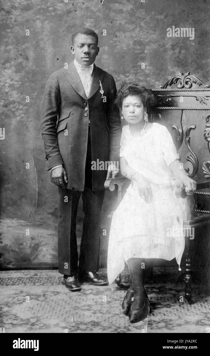 Afrikaner jungvermählte Paar am Tag nach ihrer Hochzeit für ein Studio Porträt posieren, der Mann, der an Aufmerksamkeit und in Anzug, der Frau, die in einem Sessel sitzen und ein weißes Kleid, mit Untertiteln "Beaulah und Lloyd McIlvain", 20. April 1923. Stockfoto