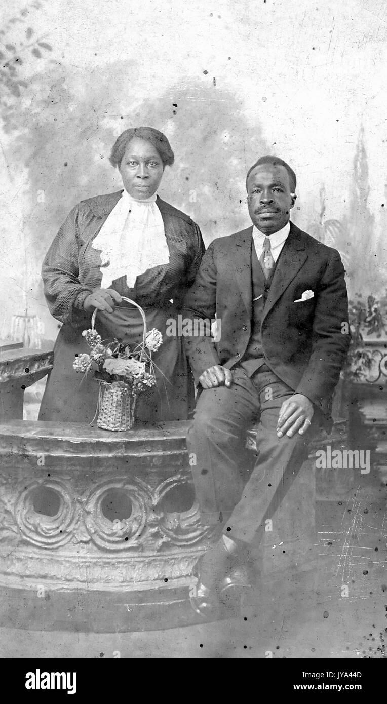Reifen Afrikanische amerikanische Paar, Mann und Frau, der Mann auf einer Arbeitsplatte in Anzug sitzt, die Frau steht hinter der Ladentheke und halten einen Korb mit Blumen, Cincinnati, Ohio, 2. Dezember 1917. Stockfoto