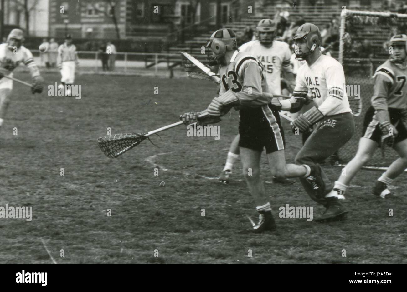 Action-Foto des männlichen Johns Hopkins University Lacrosse Spieler auf dem Feld umgeben von mehreren Yale University Spieler während eines Spiels, 1964. Stockfoto