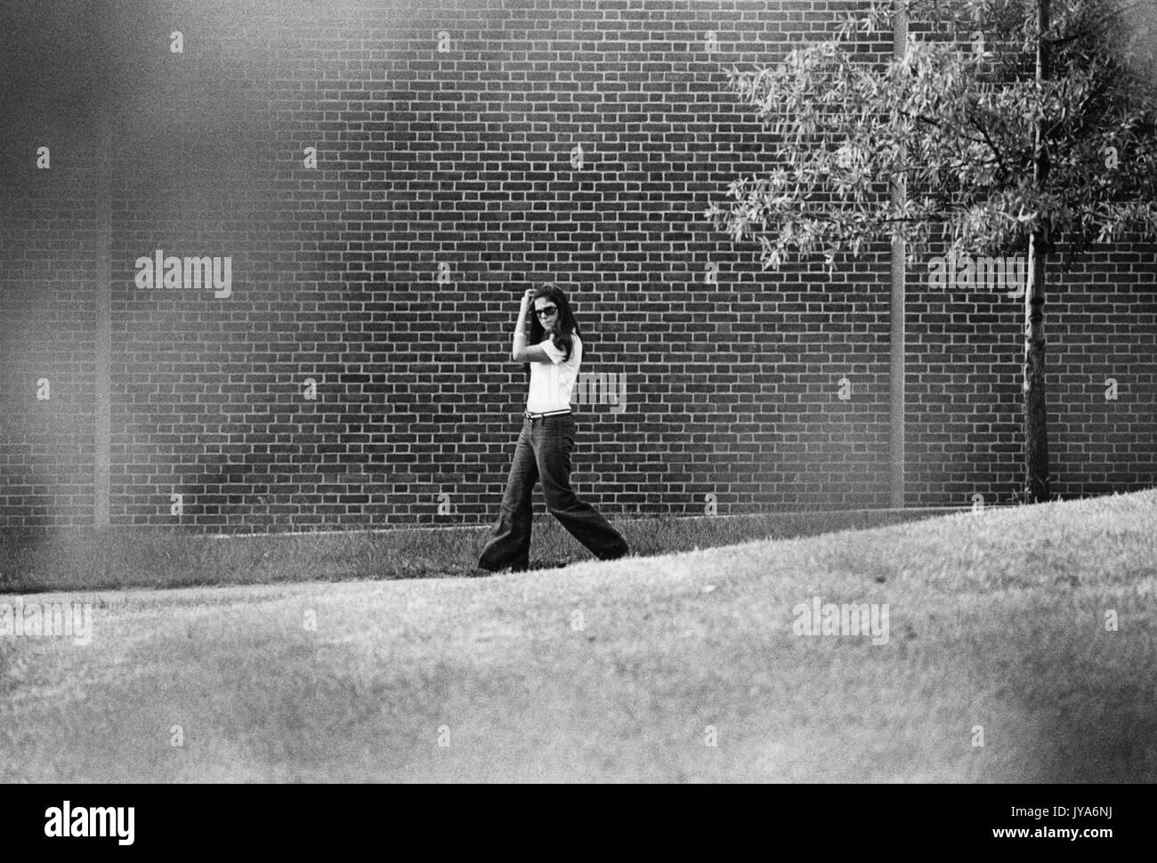 Ein Foto einer Frau, die während der ersten Jahre des Studiengangs Frauen in Baltimore, Maryland, über den Campus der Johns Hopkins University spazierend. 1970. Stockfoto