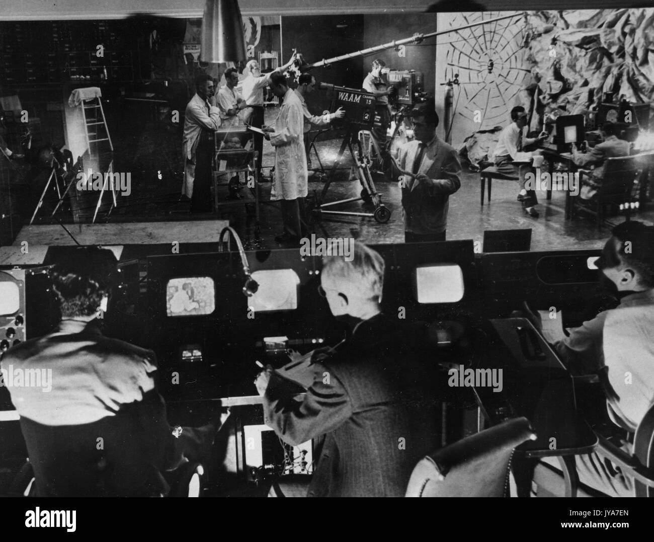 WAAM Studio Probe für 'Fear' Episode der Fernsehsendung The Johns Hopkins Science Review, 'Tony', amerikanische Fernsehmoderatorin Lynn Poole, Und 'Martin' sitzt hinter einem Kontrollpult, während WAAM Studio-Mitarbeiter mit Videogeräten an einem Shooting arbeiten, bei dem zwei Männer in Stühlen sitzen, die einander gegenüberstehen, WAAM Studio, Baltimore, Maryland, 3. Oktober 1957. Stockfoto