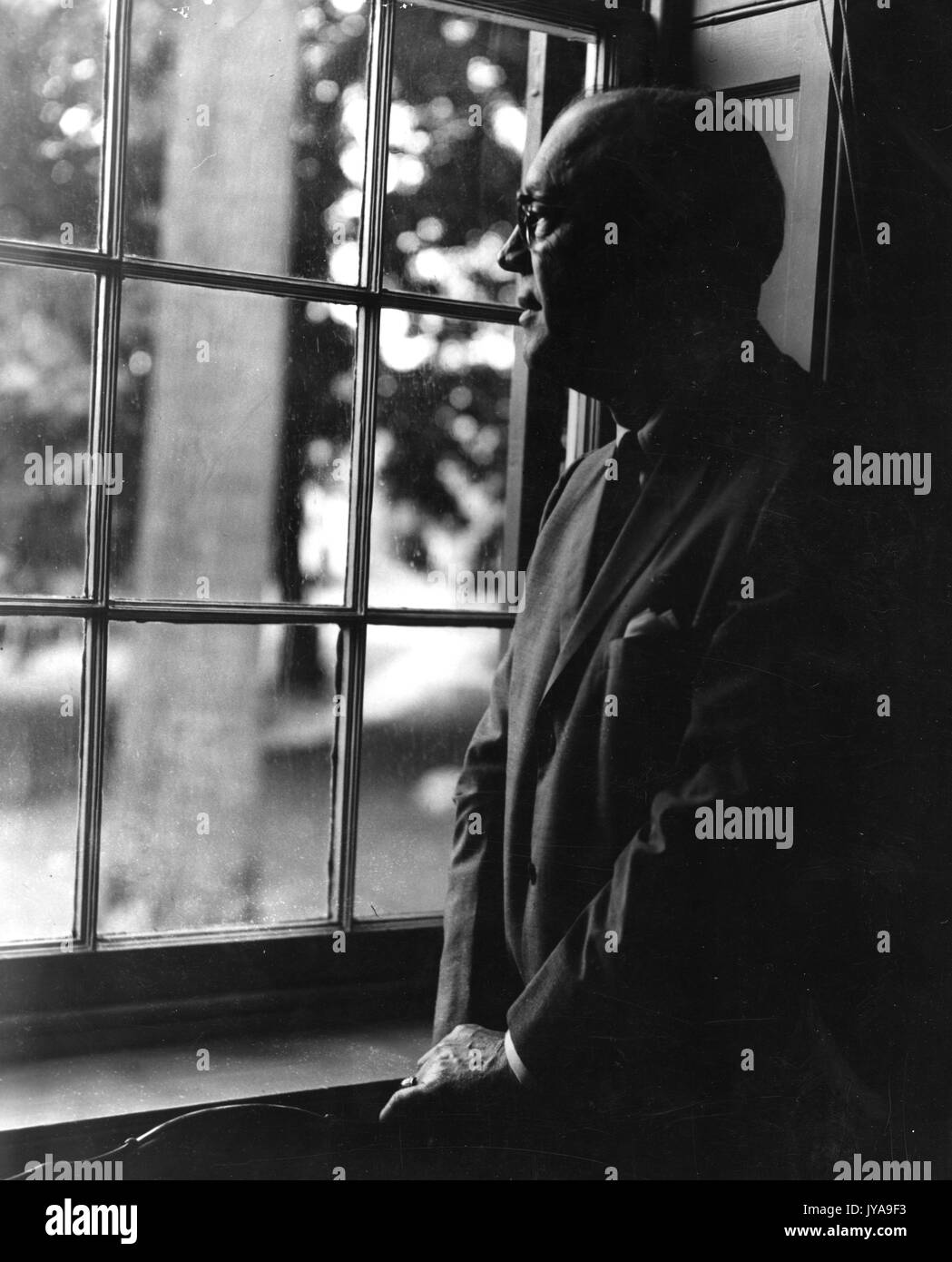 Milton Stover Eisenhower, Präsident der Johns Hopkins Universität, stehen und durch ein Fenster, 13. Juni 1963. Stockfoto
