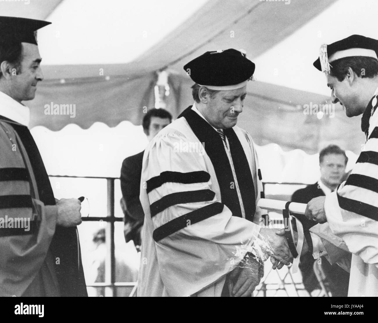 Steven Muller, Präsident der Johns Hopkins Universität, und Helmut Schmidt, der Bundeskanzler der Bundesrepublik Deutschland, Hände schütteln, während Muller Hände Schmidt einen Preis an den Zweihundertsten Einberufung an der Johns Hopkins University Homewood Campus, 16. Juli 1976 statt. Stockfoto