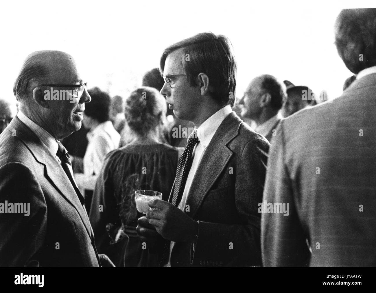 Zwei Männer in Anzügen unterhalten sich unter vielen anderen an der hundertjährigen Ball Eröffnung an der Johns Hopkins University, 1976. Stockfoto