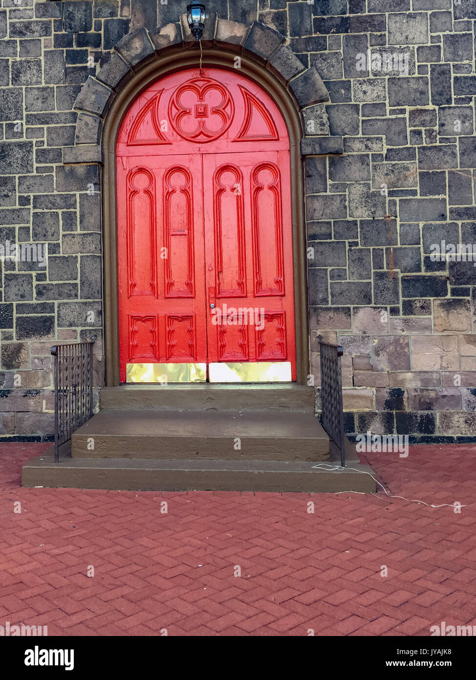 Rote bogenförmige Doppeltür mit golden Kick Platte Stockfoto