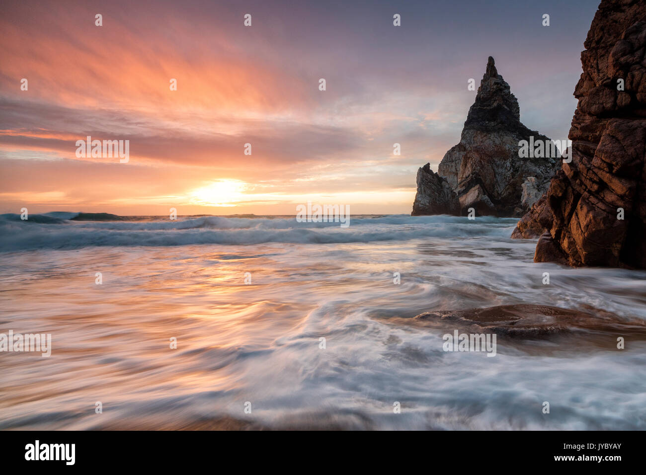 Die feurige Himmel bei Sonnenuntergang spiegelt sich auf dem Ozean Wellen und Felsen Praia da Ursa Cabo da Roca Colares Sintra Portugal Europa Stockfoto