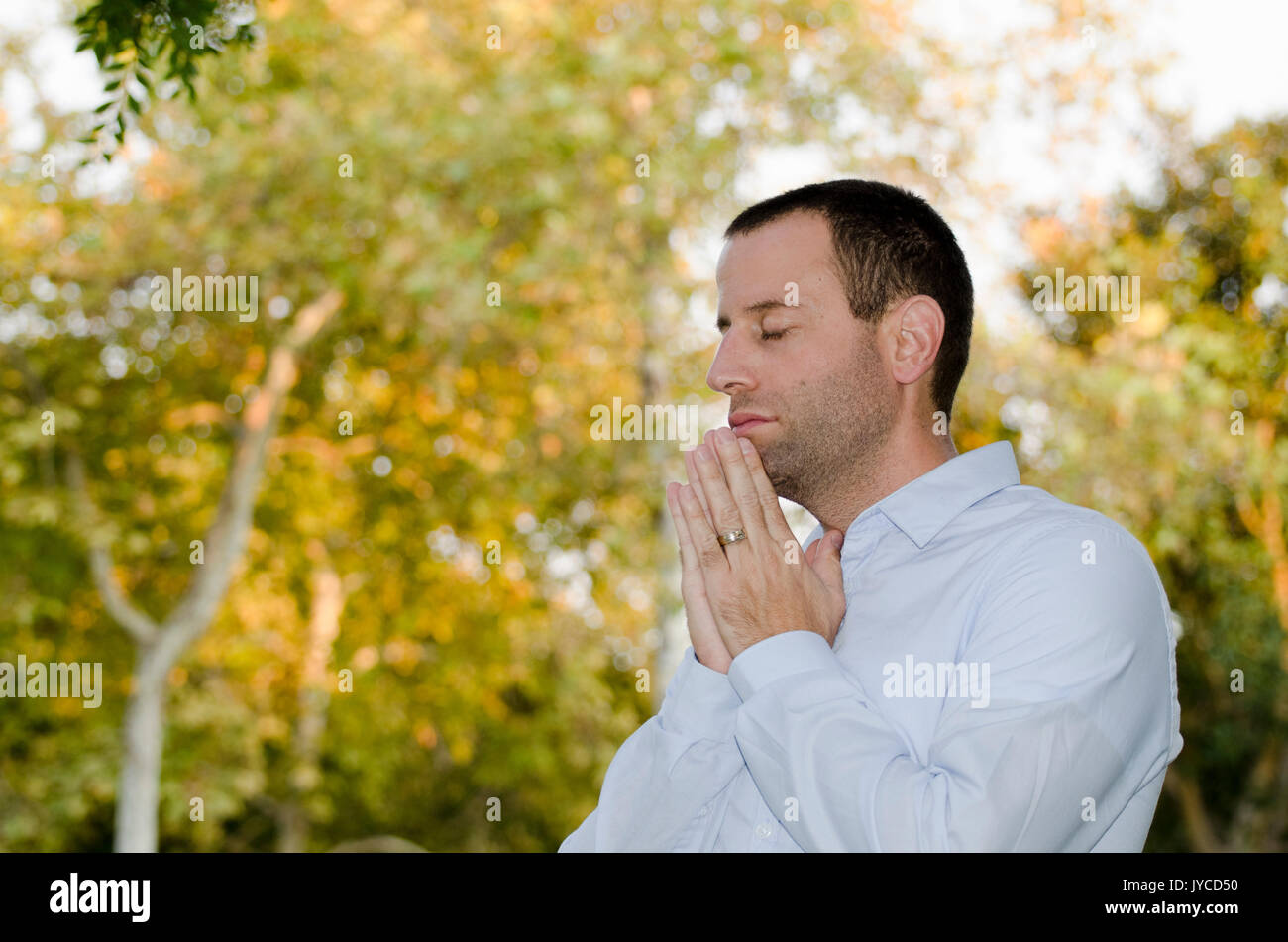 Business Mann alleine draußen mit Bäumen im Hintergrund zu beten. Stockfoto