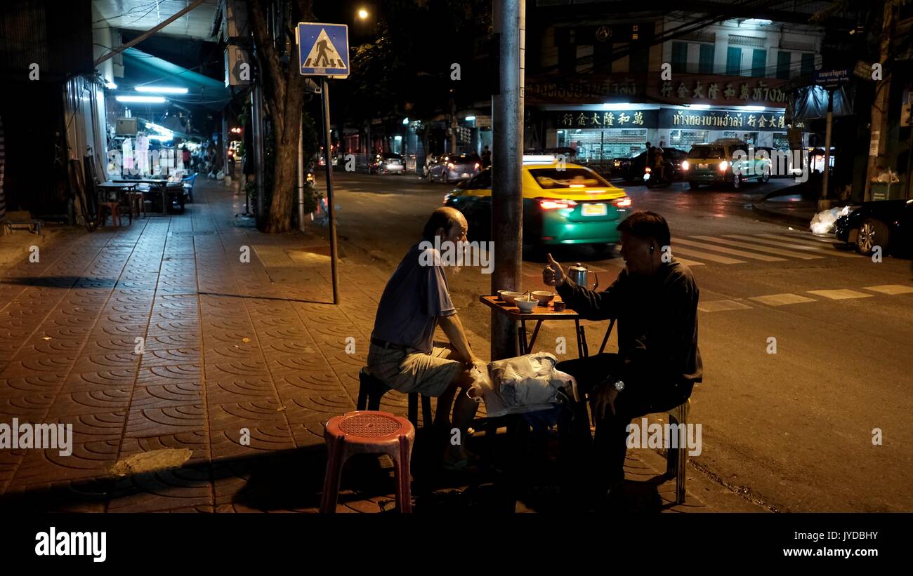 Zwei Männer Freunde Tee trinken Nachts auf die Straßen von Chinatown Charon Krung Road Bangkok Thailand, Sitzen auf Stühlen Tisch, Reden Ruhige Stockfoto