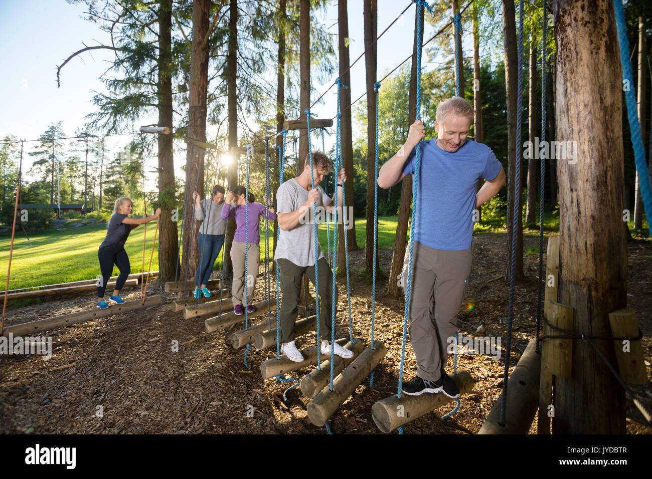 Business überqueren Swinging Logs im Wald Stockfoto