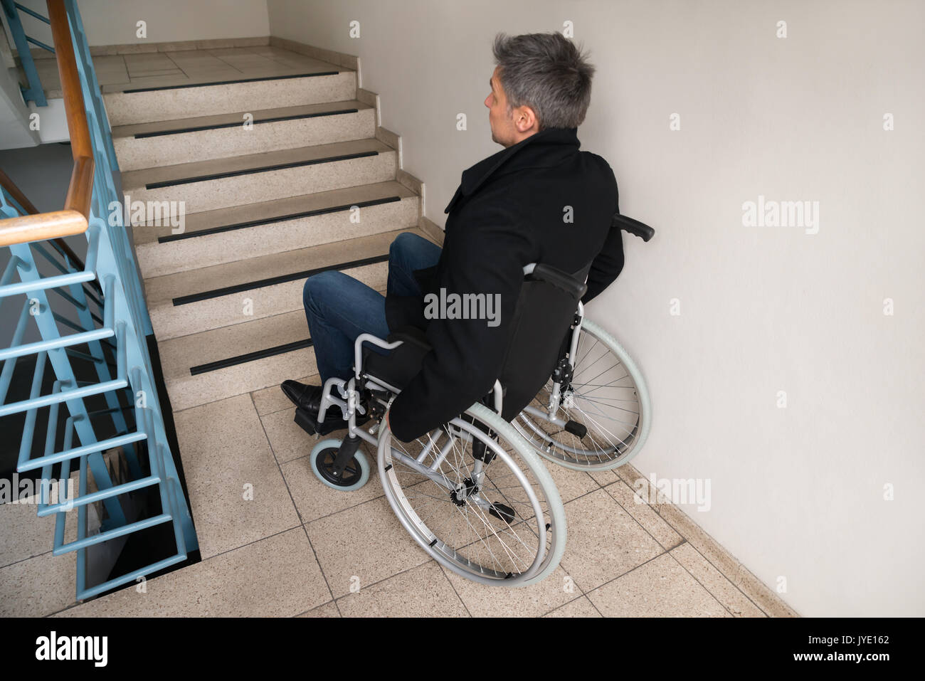 Rückansicht eines behinderten Menschen im Rollstuhl Vor der Treppe Stockfoto