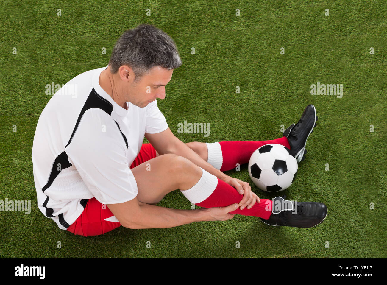 Männliche Fußball Spieler mit Verletzungen im Bein auf dem Feld Stockfoto