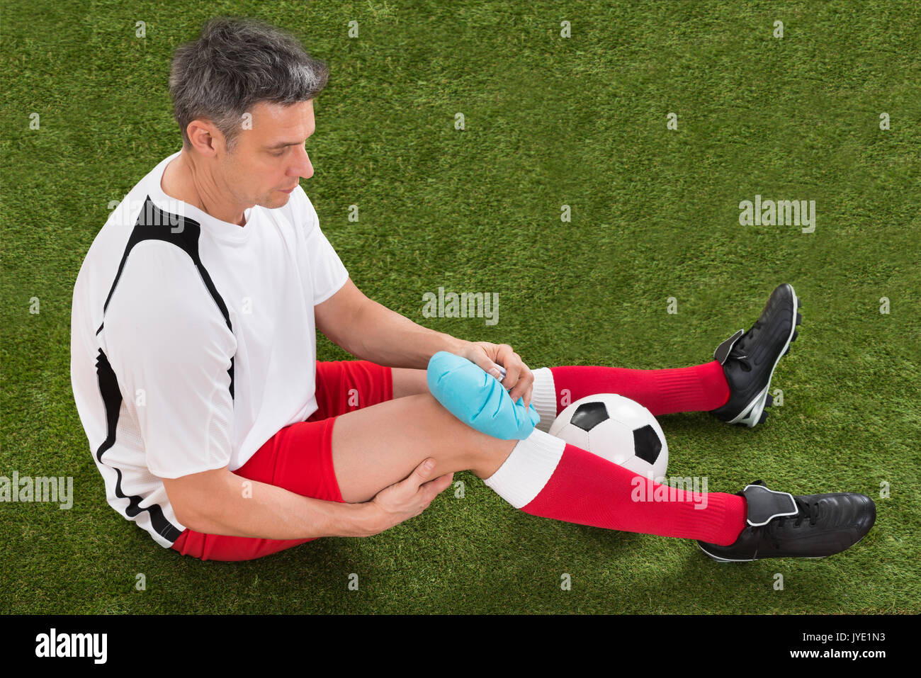 Männliche Fußballspieler Vereisung Knie mit Eis auf dem Feld Stockfoto