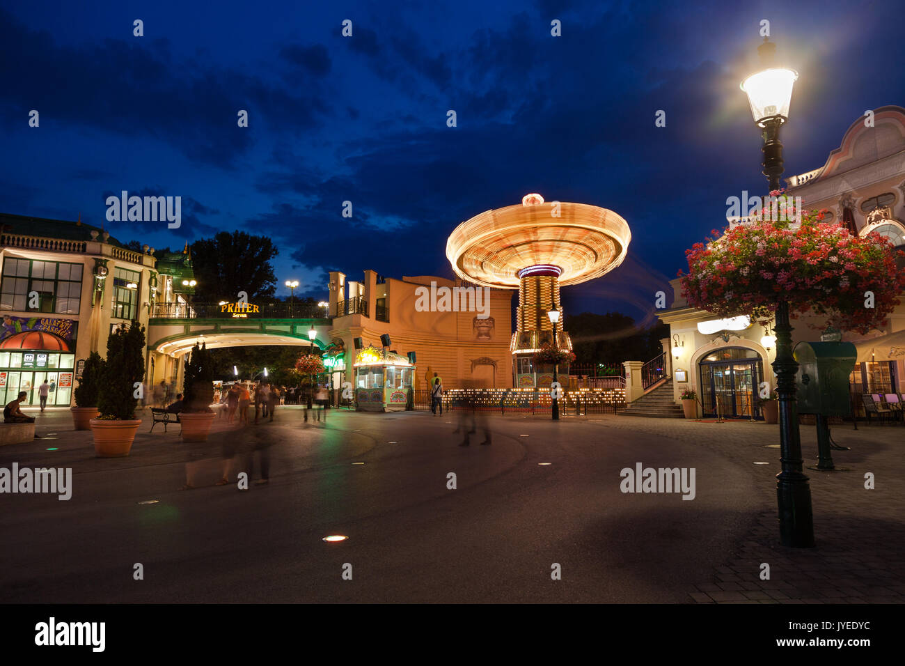 Vergnügungspark mit Riesenrad in Aktion in der Abenddämmerung mit Licht an in Wien, Österreich, Europa. Stockfoto