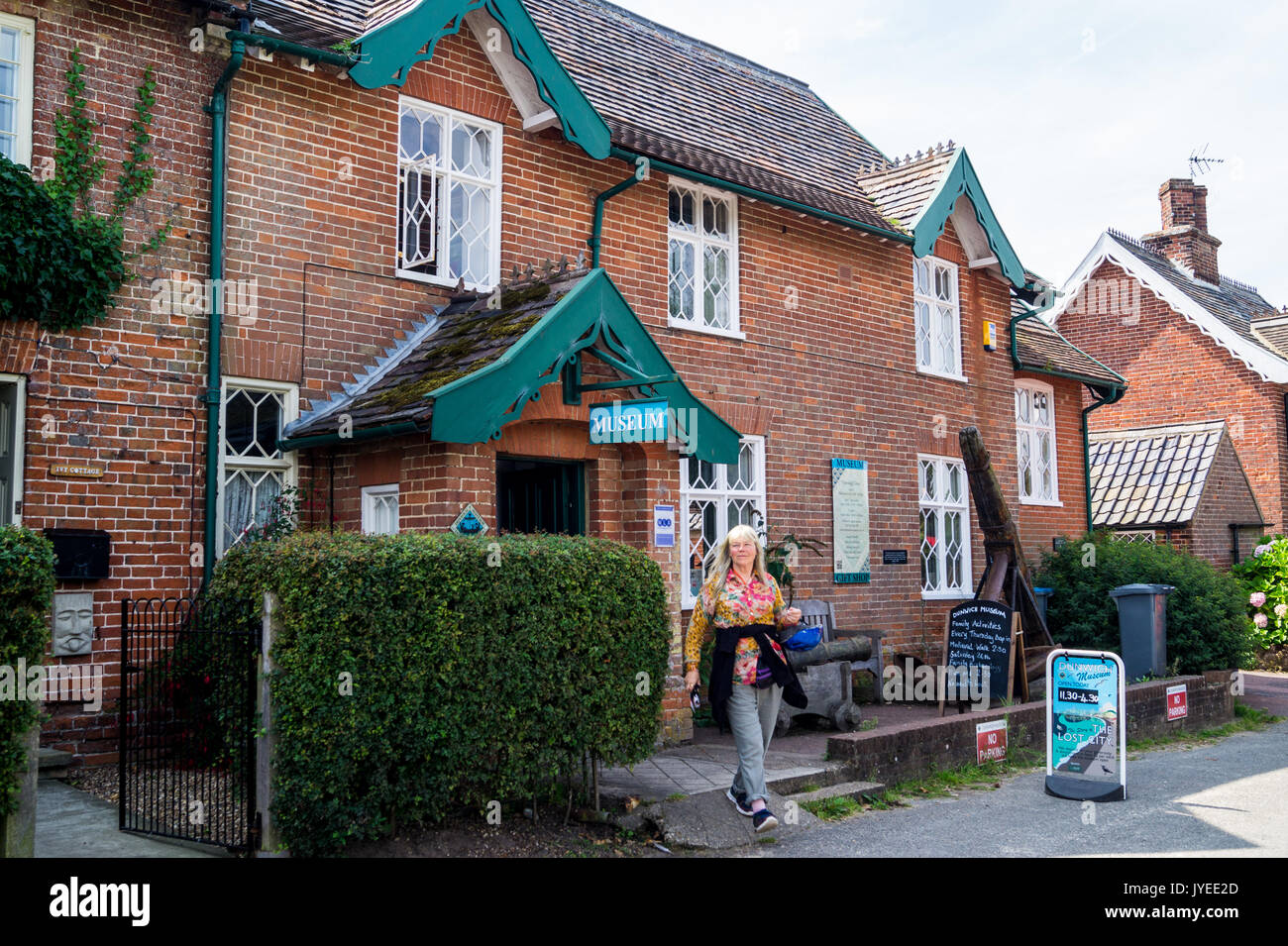 Eine Frau in einer farbenfrohen Bluse außerhalb Dunwich Museum, Suffolk, England Stockfoto