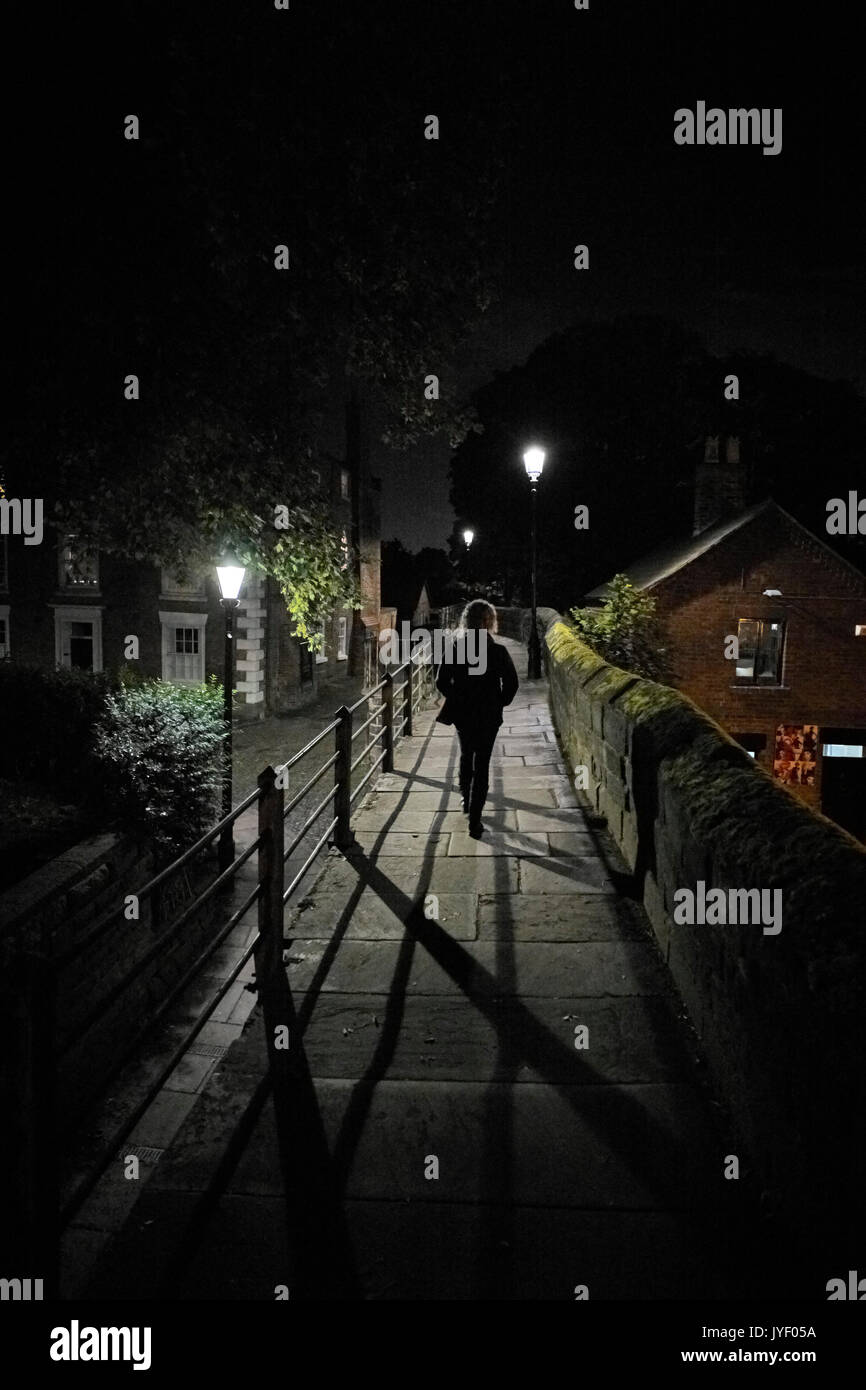 Frau gehen weg von der Kamera in der Nacht in der Stadt Stockfoto
