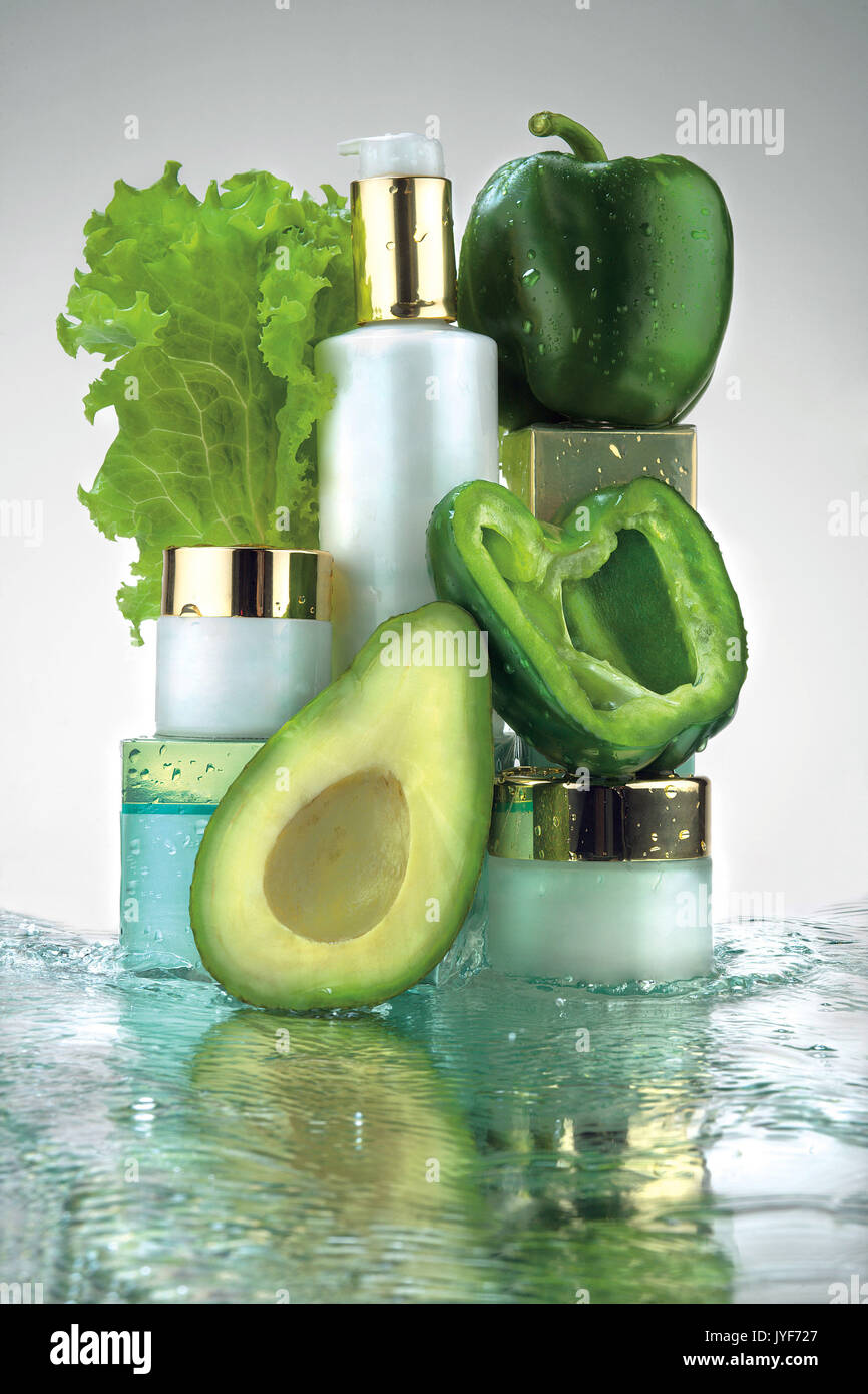 Creative Foto von verschiedenen Kosmetika Gläser und grünes Gemüse in Wasser spritzen. Stockfoto