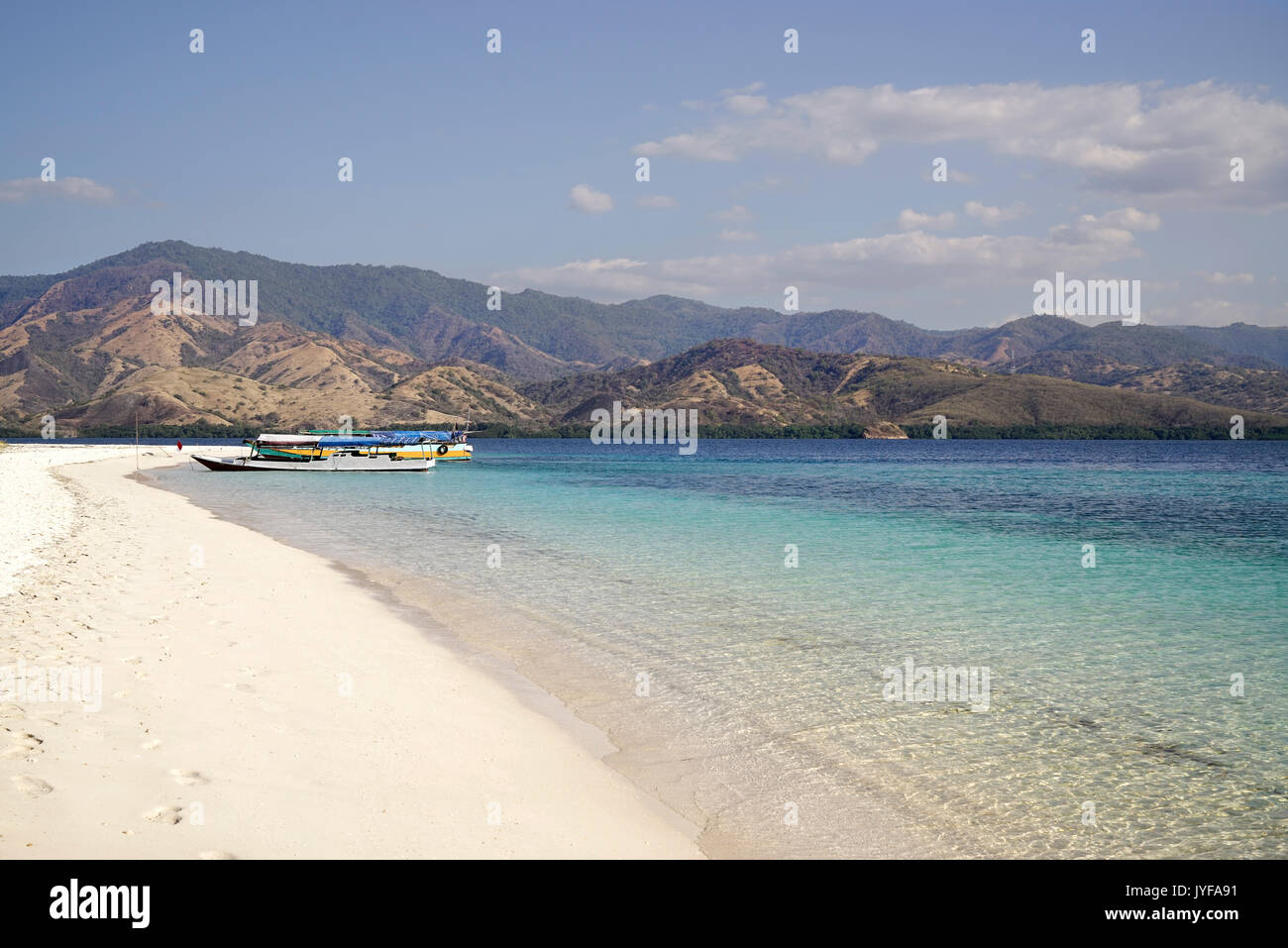 White Sand Beach mit zwei Boote am Ufer am Mittag mit Blick auf den breiten Insel mit grüner Vegetation im te Ocean, Flores Indonesien. Stockfoto