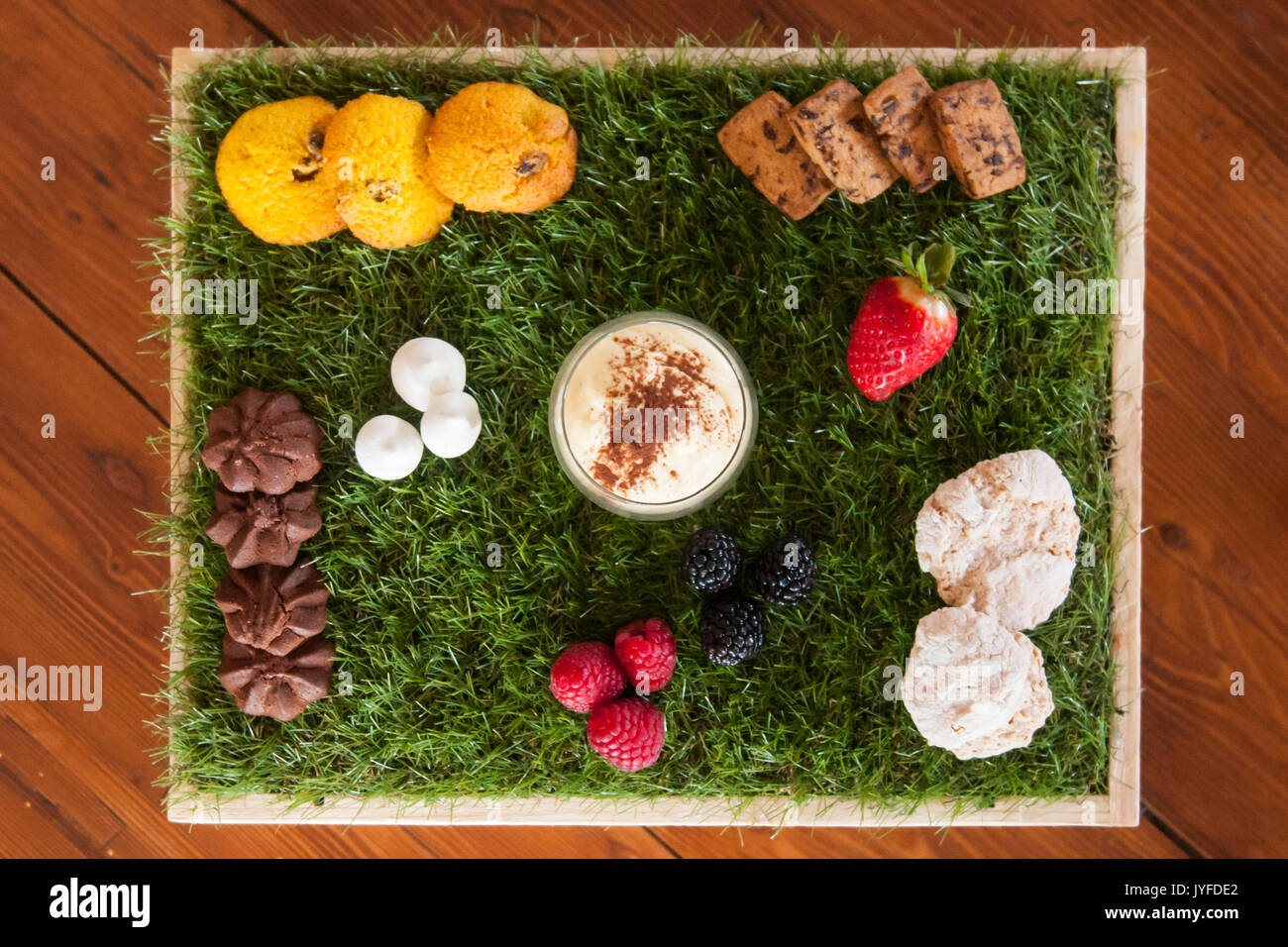 Ein Dessert mit Gebäck und frischem Obst auf einem Teppich aus Gras Stockfoto