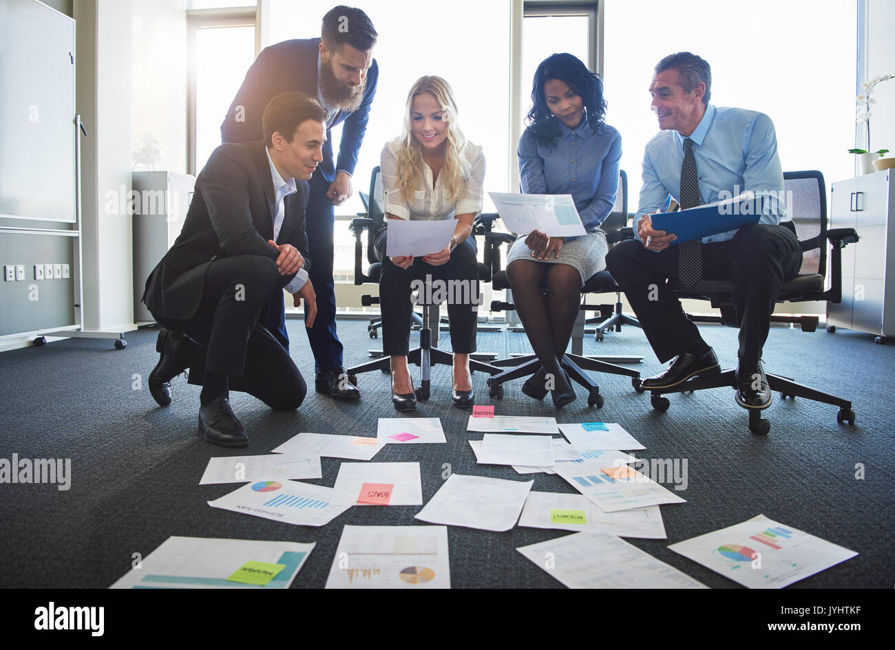 Gruppe von verschiedenen Geschäftsleute gemeinsam Brainstorming mit Dateien, die auf dem Boden, während in einem modernen Büro arbeiten Stockfoto