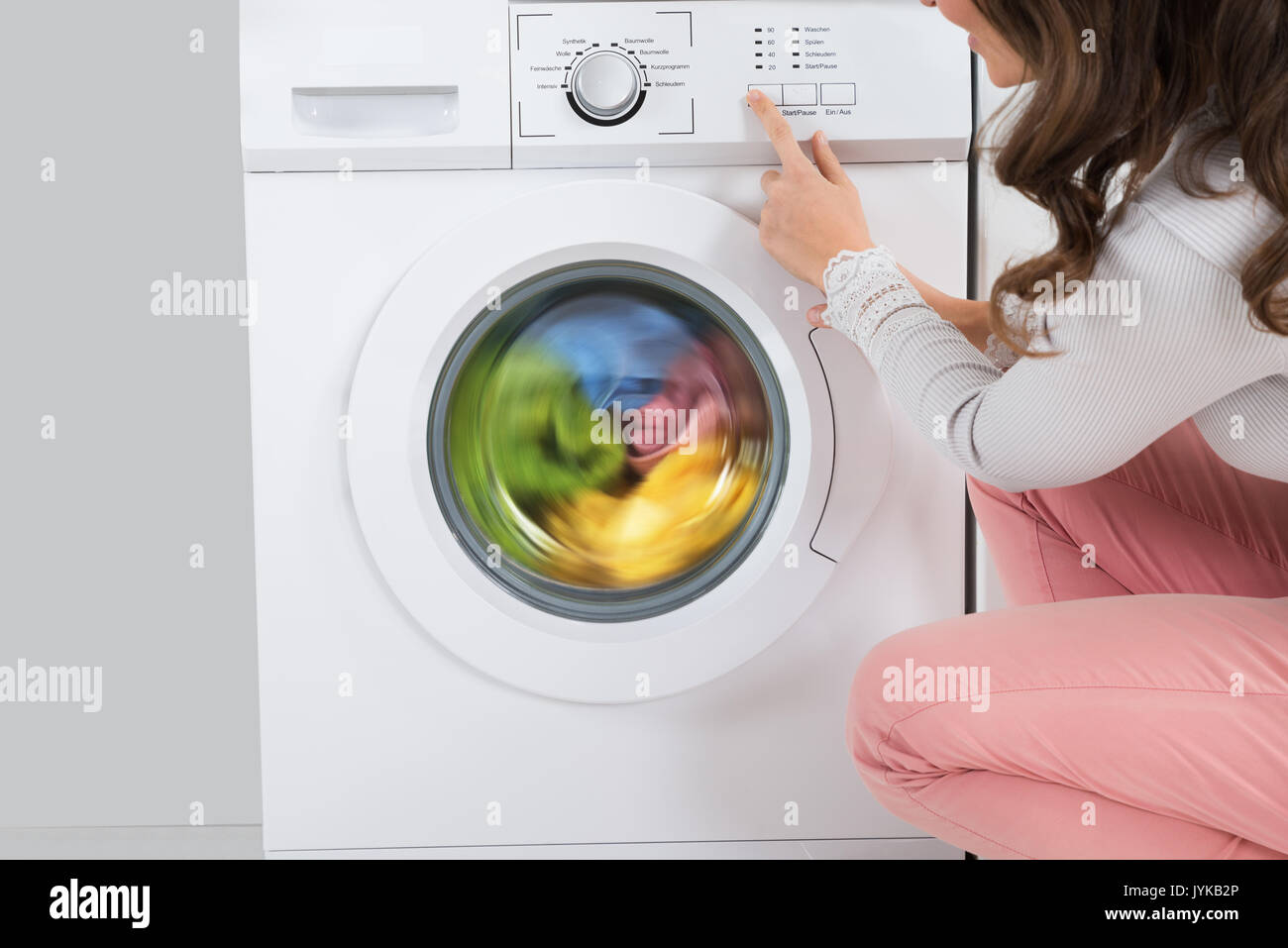 Nahaufnahme der jungen Frau durch Drücken der Taste der Waschmaschine in der Küche Stockfoto