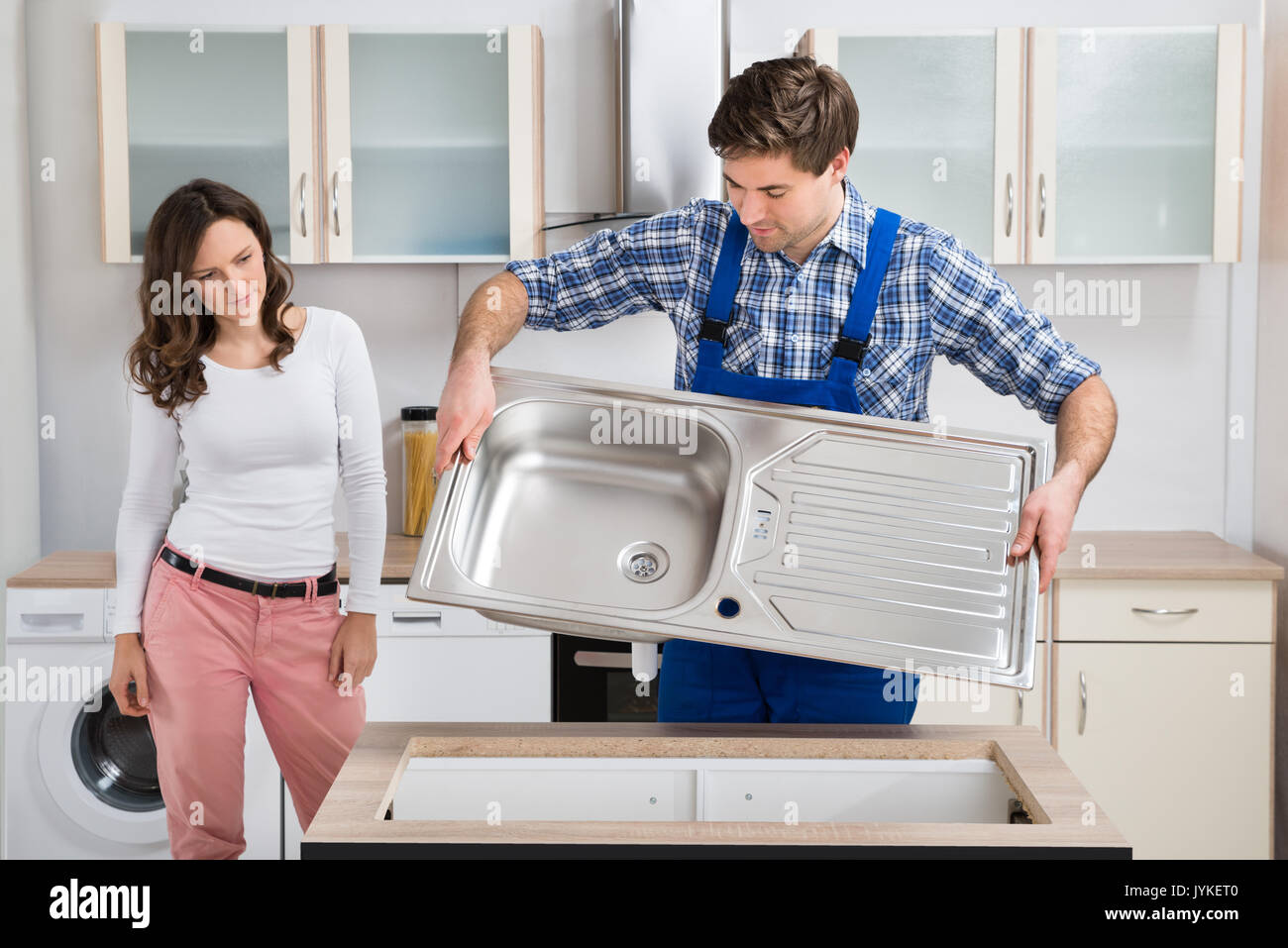 Junge Frau mit männlichen Arbeitnehmers Ausführung Edelstahl Spülbecken in der Küche Stockfoto