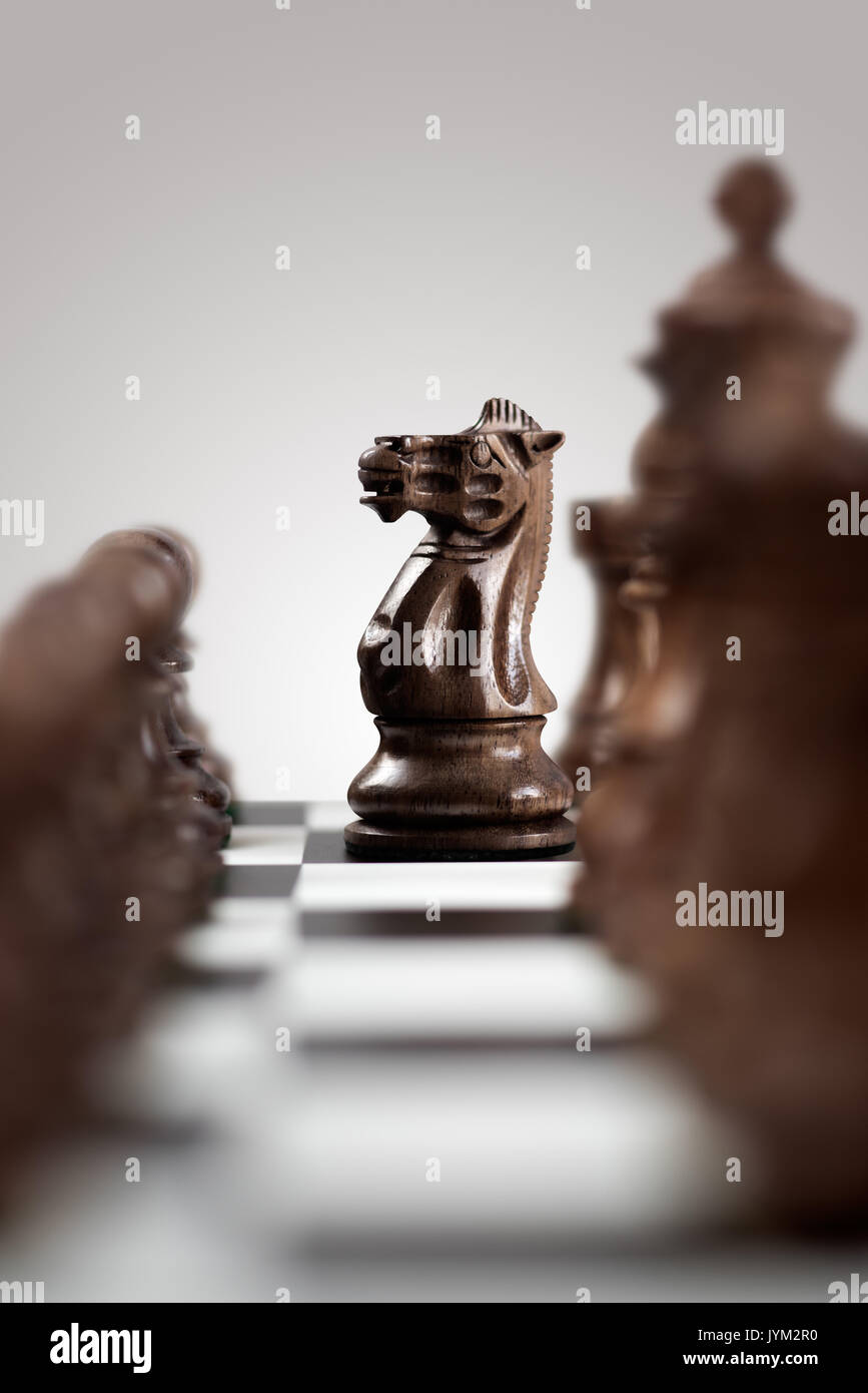 Creative Business Konzept Foto von einem schwarzen Holz- Schach Ritter zu Schachfiguren auf dem Schachbrett bereit für einen L-förmigen bewegen. Stockfoto