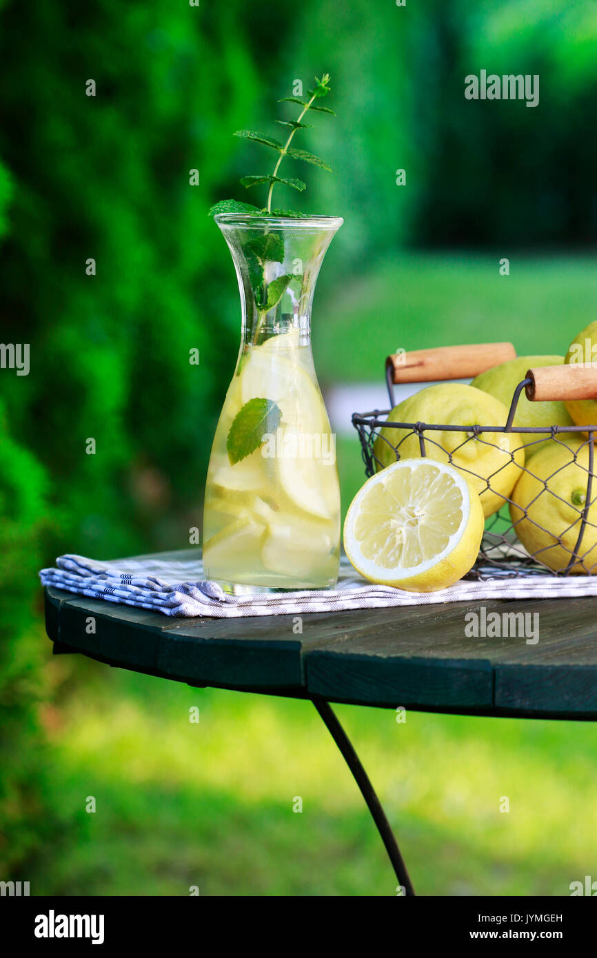 Limonade in der Flasche und frisches Obst im Drahtkorb. Sommer Garden Party. Stockfoto