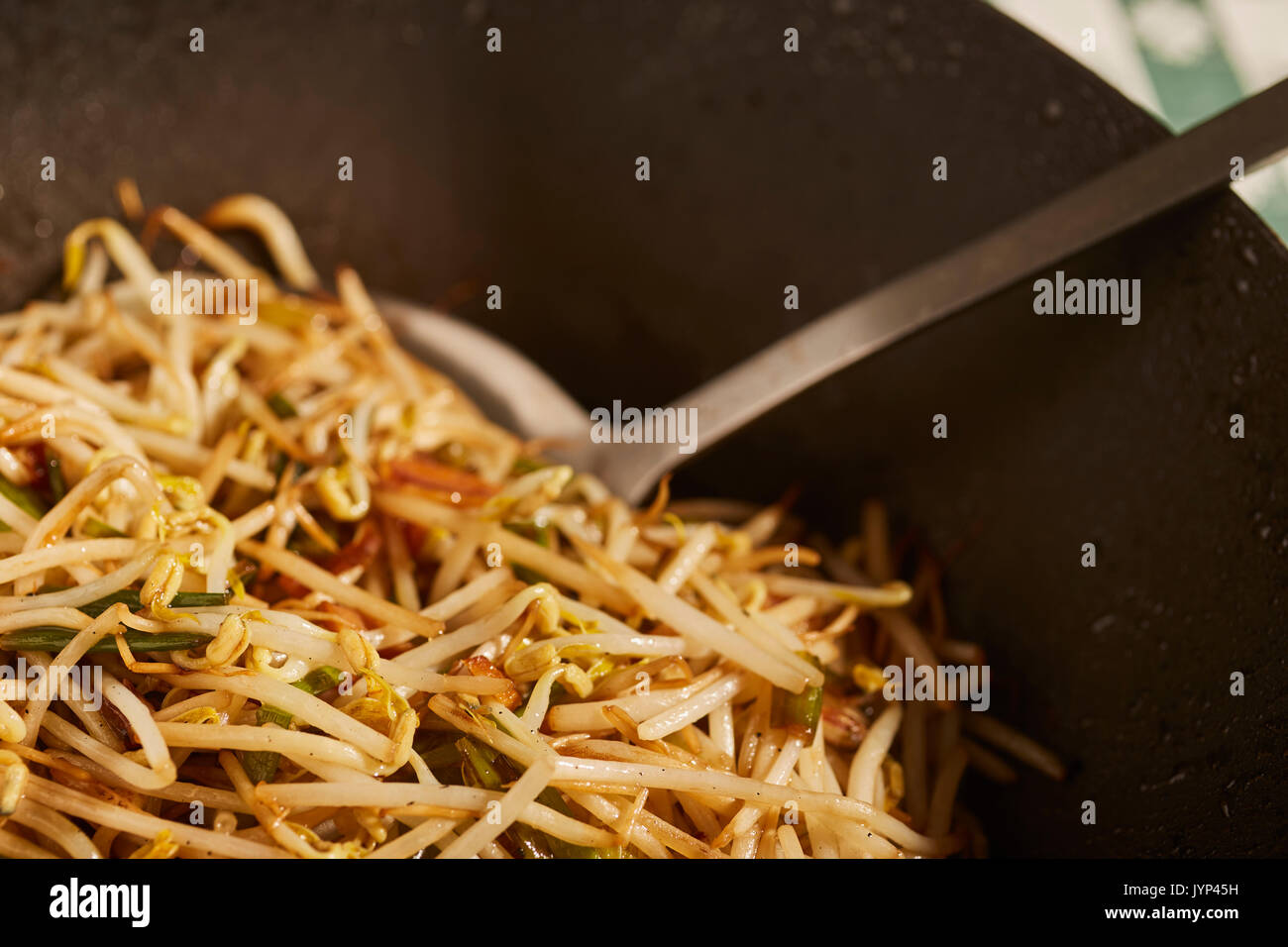 Gebratene Sojabohnensprossen und Frühlingszwiebeln in einem schwarzen Stahl wok Rühren Stockfoto