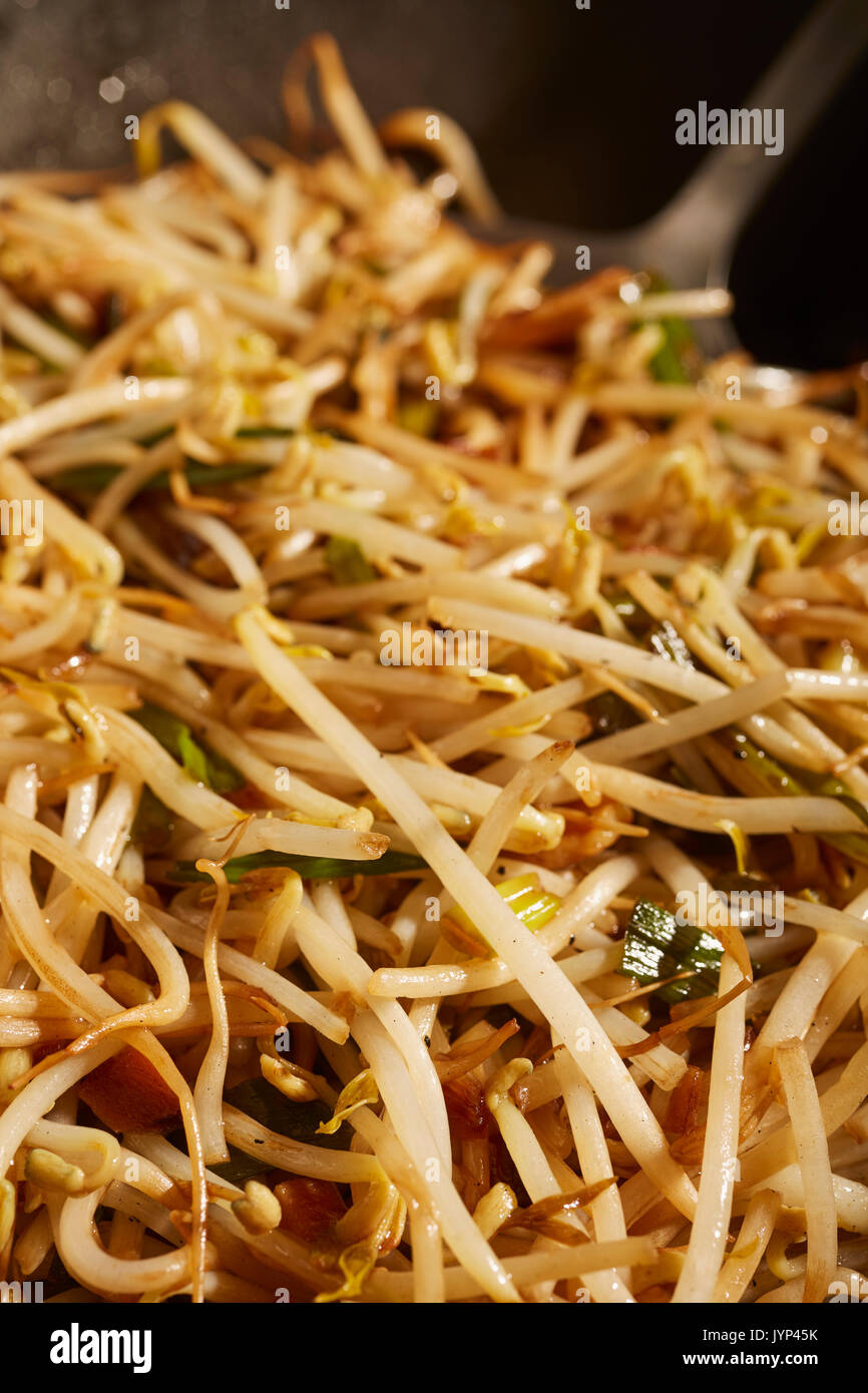 Gebratene Sojabohnensprossen und Frühlingszwiebeln in einem schwarzen Stahl wok Rühren Stockfoto