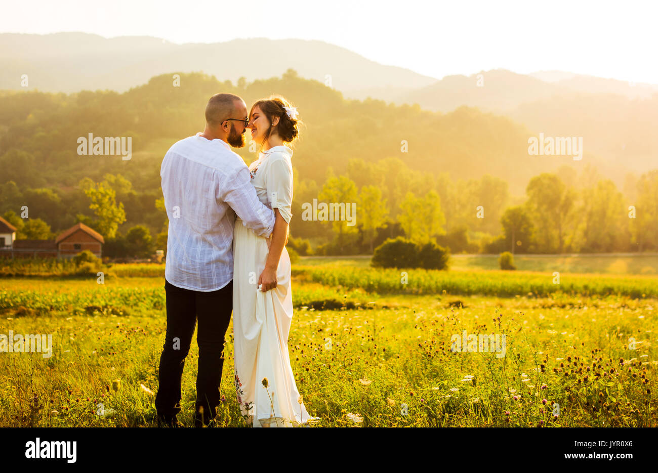 Paar küssen bei einem romantischen Sonnenuntergang in das Feld Stockfoto