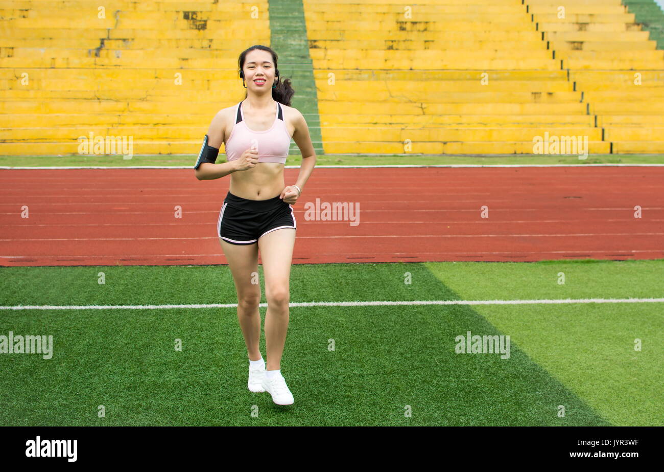 Mädchen joggen mit Smartphone auf einem Fußball Feld Stockfoto