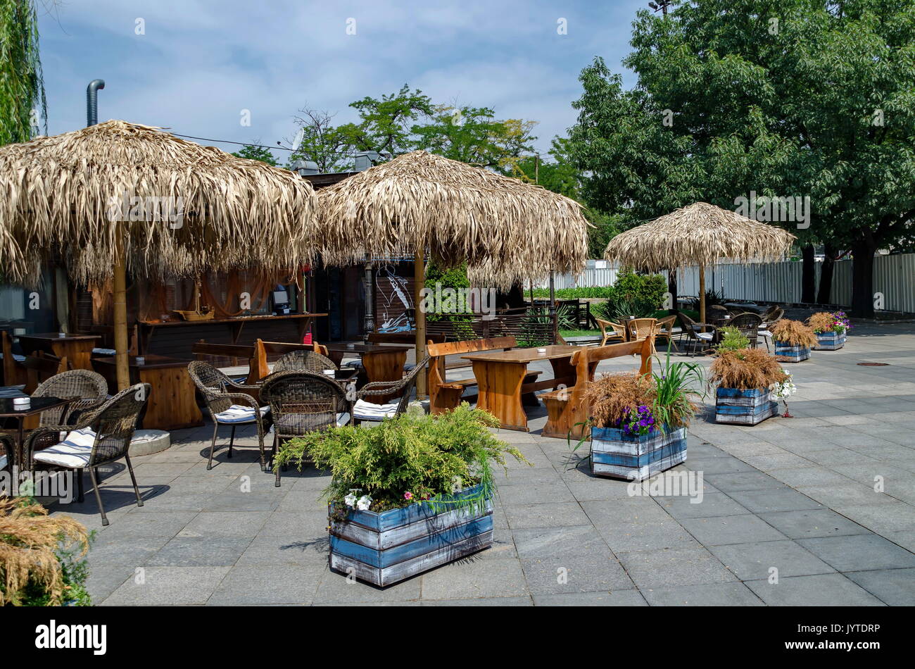 Blick auf die gemütliche Frühstücksecke für Sommer Erholung unter Palm Sonnenschirm mit Bar, Tisch, Stuhl und Bank aus Holz, park Borisova Gradina, Sofia, Bulgarien Stockfoto