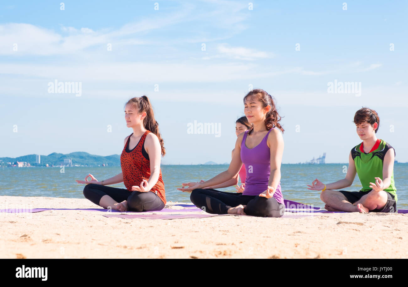 Yoga am Meer Strand in sonniger Tag, Gruppe von Menschen Lotus tun Pose mit Clam emotion Entspannung, Meditation, Wellness und gesunde Balance Lifestyle. Stockfoto